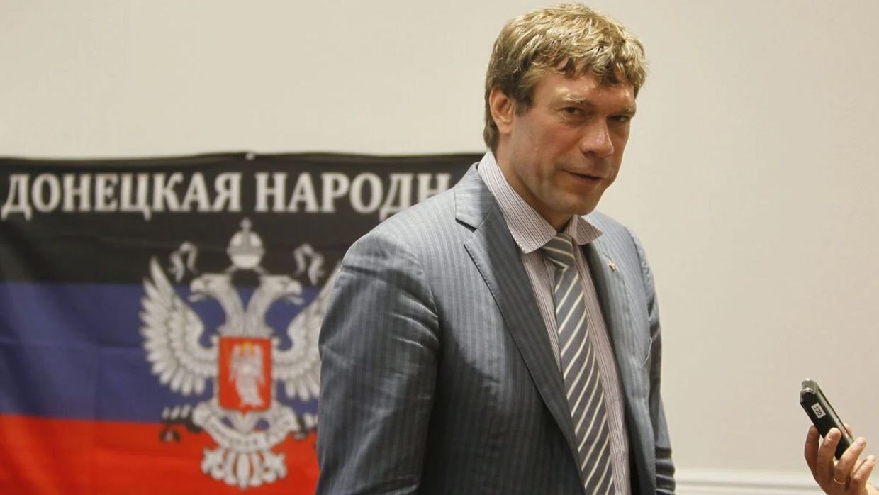 Чоловік у сірому костюмі на тлі прапора так званої «ДНР». Ілюстрація до матеріалу про конфлікт Олега Царьова з російськими пропагандистами.