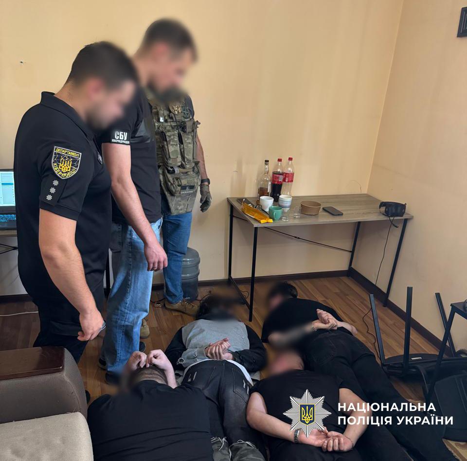 Троє чоловіків лежать на підлозі, поруч стоять правоохоронці.