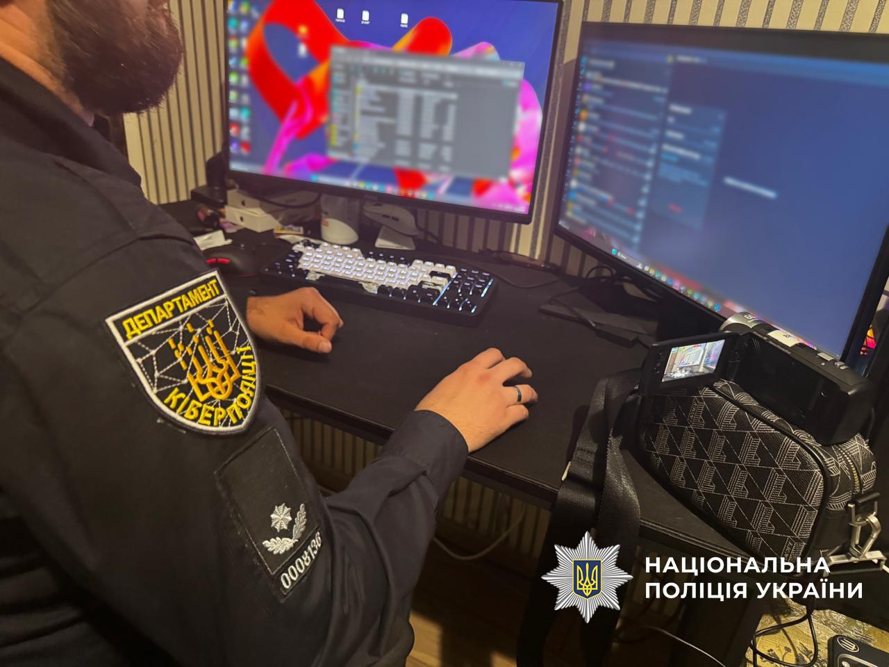 Кіберполіцейський працює за столом із двома моніторами та комп’ютерною технікою.