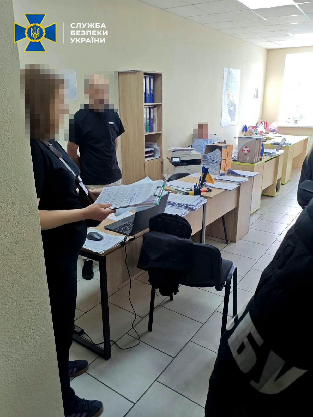 Жінка тримає папку з документами в офісі, поруч стоять люди із заблюреними обличчями.