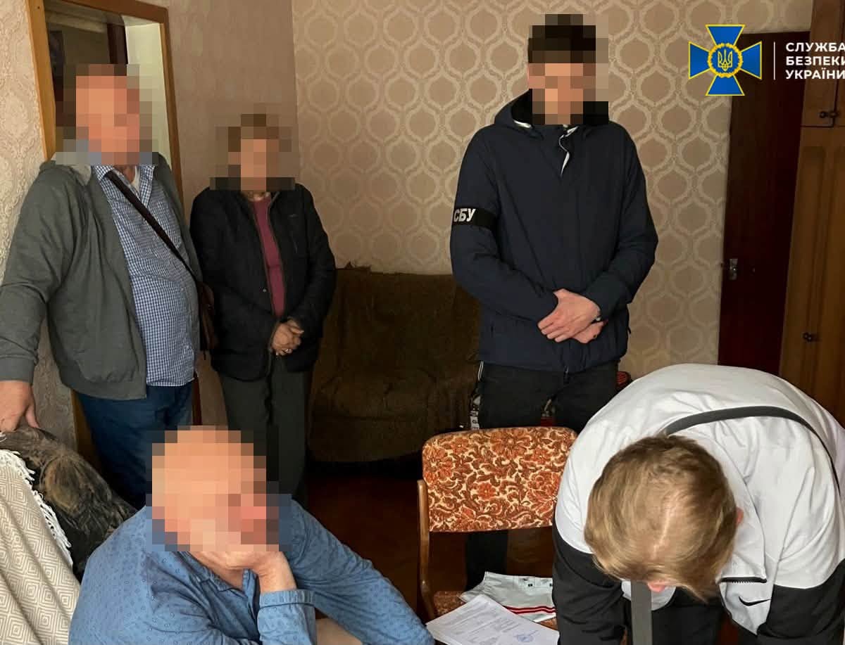 У кімнаті перебувають кілька людей із заблюреними обличчями, один із них нахилився над документами.
