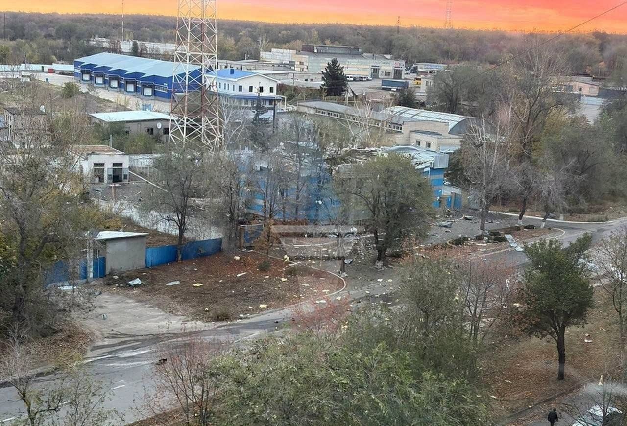 Промислові будівлі, металева вежа, дерева та дорога, на якій розкидані уламки.