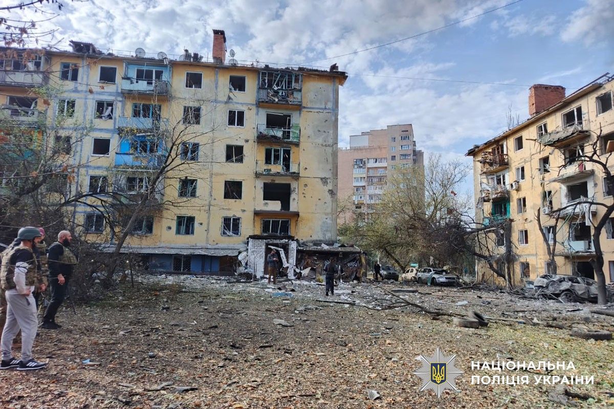Напівзруйнована одноповерхова цегляна будівля. Навколо купи битої цегли, уламки конструкцій та пошкоджені дерева.